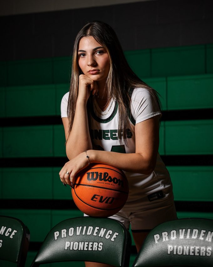 Pioneers basketball player sitting in bleachers with Wilson basketball