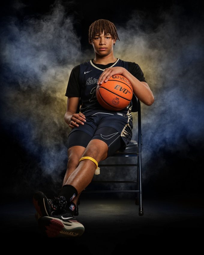 Basketball player sitting on chair holding ball with dramatic smoke background