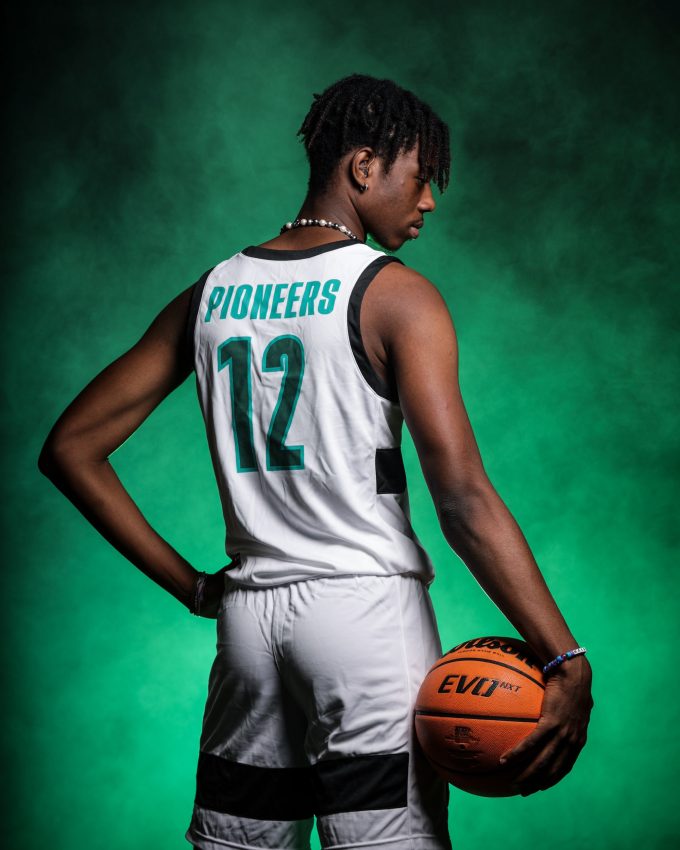 Pioneers basketball player #12 holding ball from behind against green backdrop