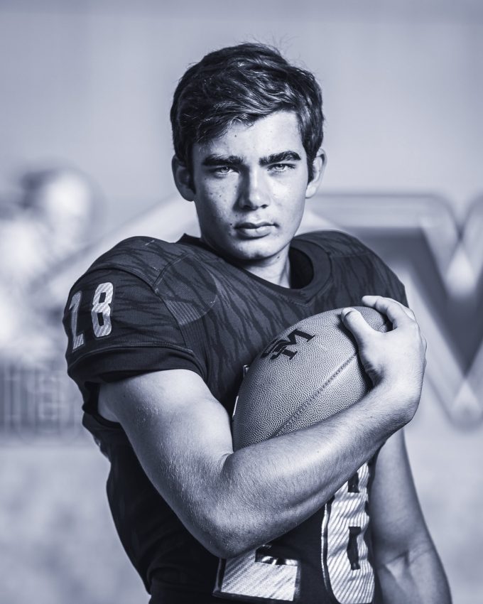 Football player #8 holding football in black and white portrait