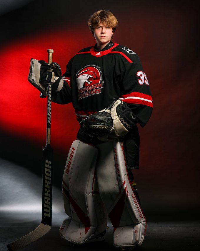 Hockey goalie in Burbank Cougars jersey with full pads and stick