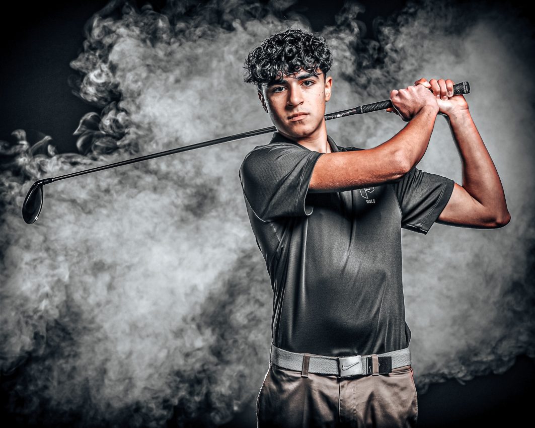 Golfer in follow-through swing pose against smoke backdrop