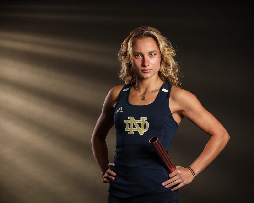 Notre Dame track athlete holding relay baton in uniform