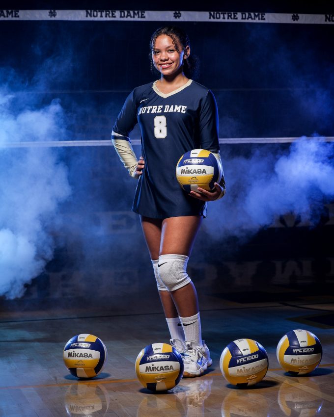Notre Dame volleyball player #8 posing with Mikasa volleyball in blue smoke